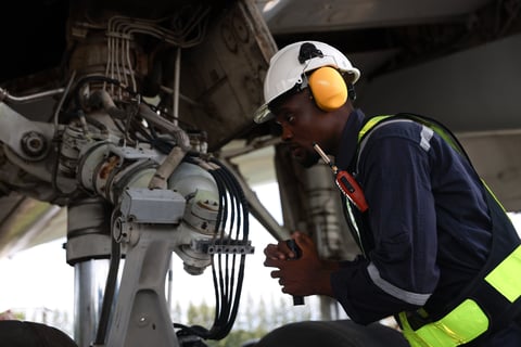 Black male aircraft mechanic using hand tools to work on airplane inspection and maintenance in hangar