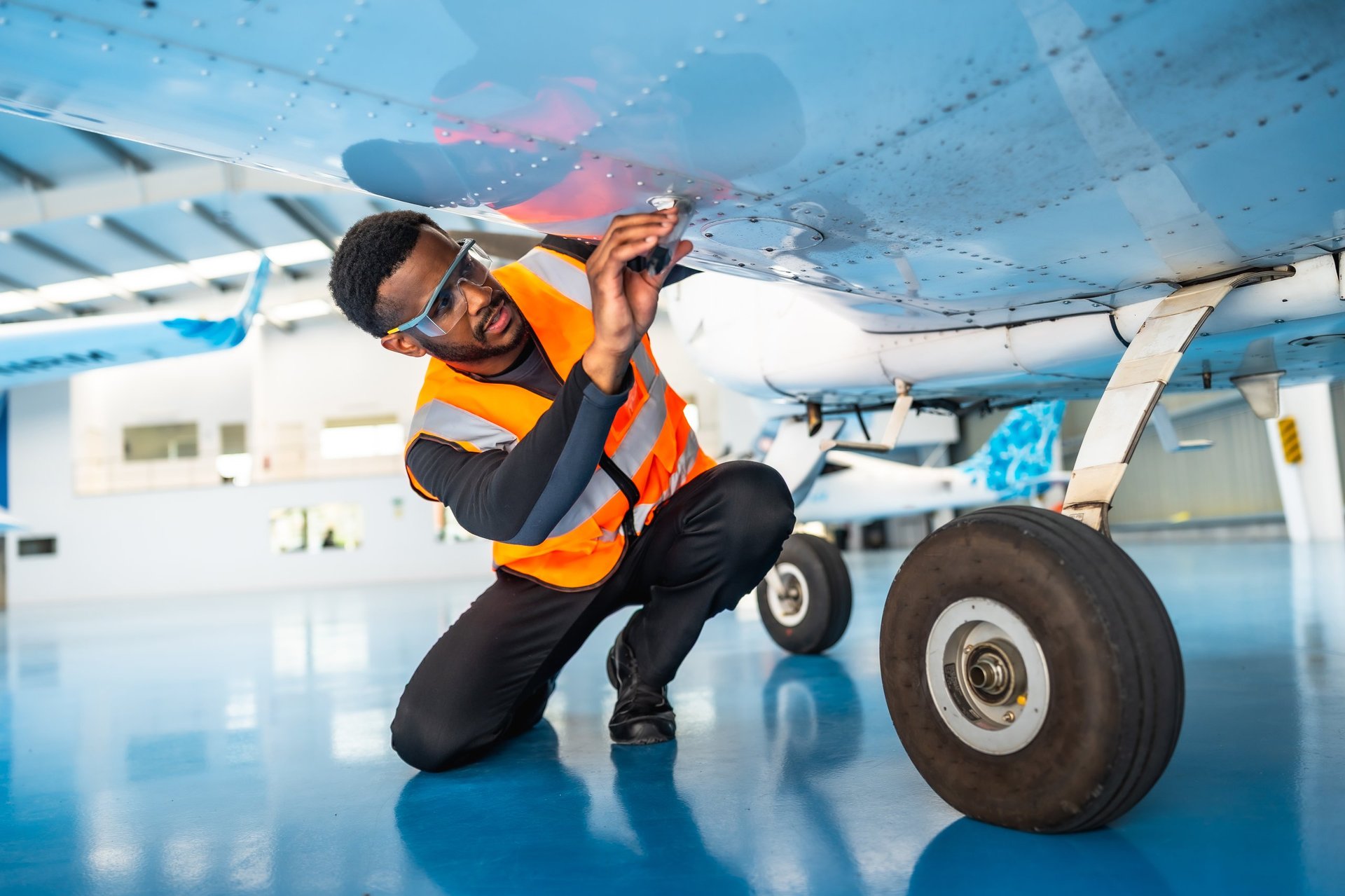 Ghanaian aircraft maintenance engineer inspecting wing