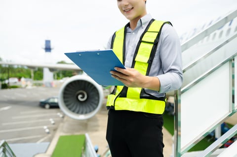Ground crew engineer in safety vest using walkie talkie during airplane inspection