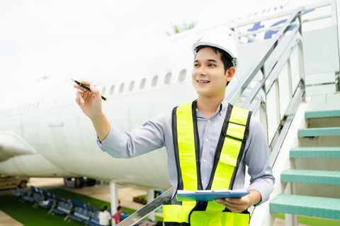 Ground crew engineer with safety helmet pointing at aircraft documents