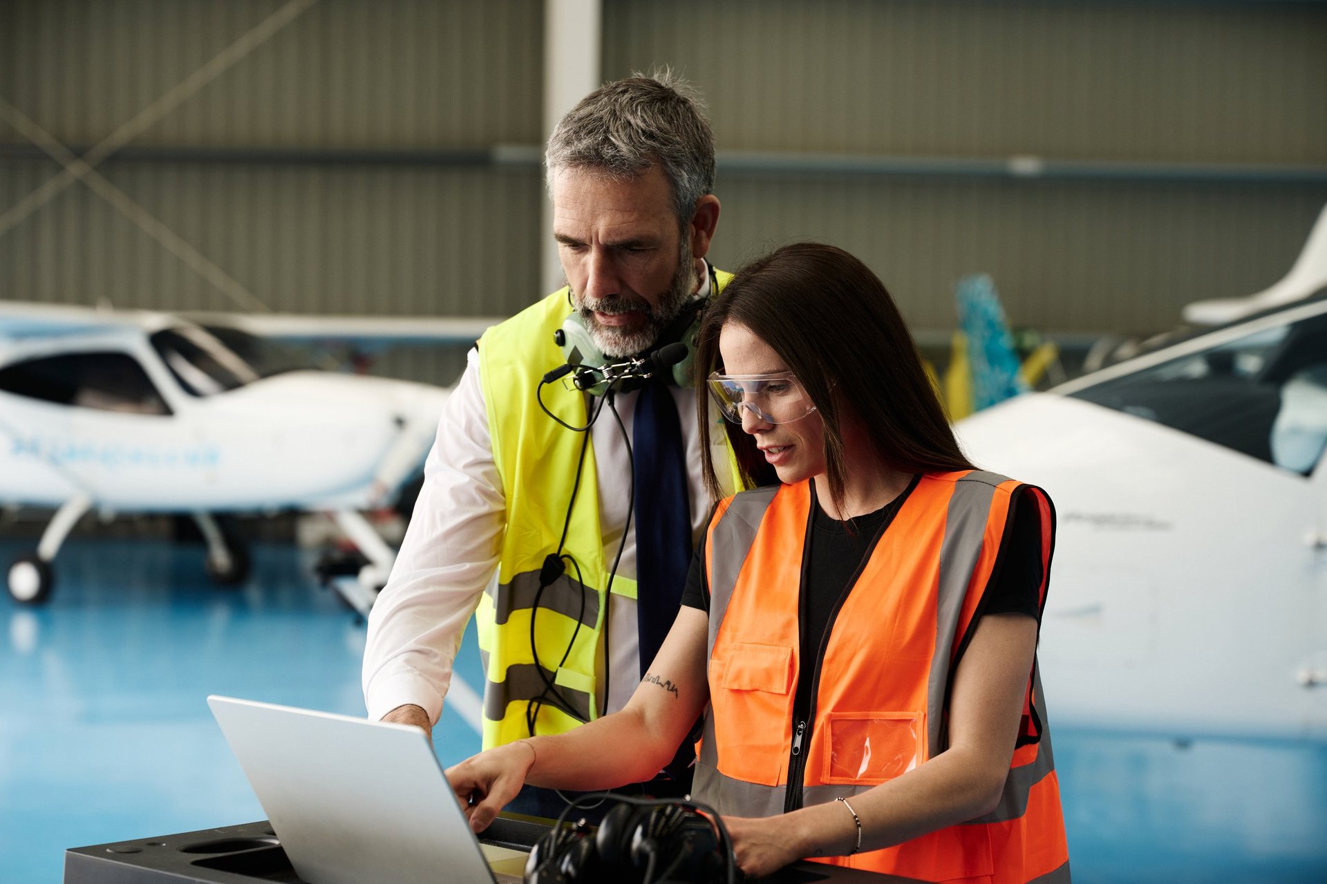 Two Ghanaian aviation engineers collaborating on a laptop in an aircraft hangar